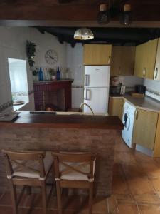 a kitchen with a counter and two chairs in it at Casa rural TIO PEDRITO in Robledillo