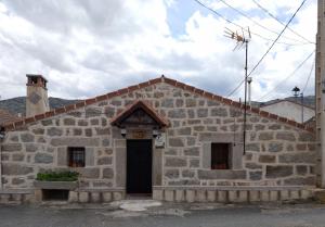 a small stone building with a black door at Casa rural TIO PEDRITO in Robledillo +4 photos