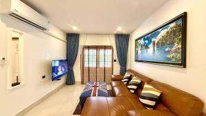 ein Wohnzimmer mit einem braunen Ledersofa und einem TV in der Unterkunft Secret Valley near Phuket Town in Kathu
