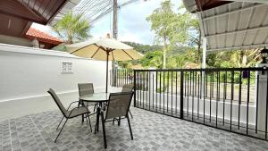 eine Terrasse mit Tisch und Stühlen und einem Sonnenschirm in der Unterkunft Secret Valley near Phuket Town in Kathu