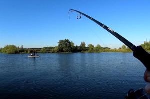 a person holding a fishing rod in a boat on a lake at Lusin hyuratyn in Dzoraget