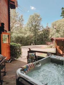 a hot tub on a deck with a table and bench at Cuckoo Lodge in Caerwys