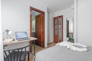 a bedroom with a bed and a desk with a laptop at Terreo 10-12 in A Coruña