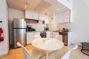 a kitchen with a table and chairs and a refrigerator at Reem Island Modern 1BR Pool, Gym, City View in Abu Dhabi
