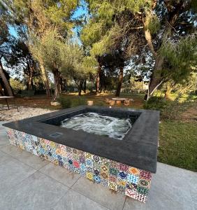 a hot tub in a park with trees in the background at Villa Kalorama-private pool & Hot Tub in San Vito dei Normanni