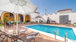 a pool with chairs and an umbrella next to a house at Villa el Señorío Alameda by Ruralidays in Antequera