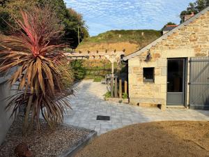 a stone house with a palm tree in a yard at Maison de La Rive in Ploëzal