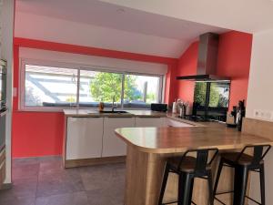 a kitchen with red walls and a wooden counter top at Maison de La Rive in Ploëzal