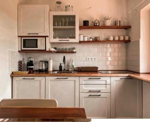 a kitchen with white cabinets and a microwave at Diófás Ház in Siklós +13 photos