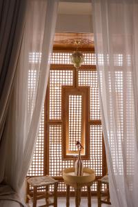 Habitación con ventana con cortinas y mesa. en Riad Al Muhandiz Peaceful Duplex Suites near Jemaa El Fna, en Marrakech
