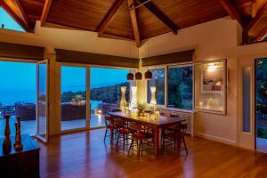 an open dining room with a wooden table and chairs at Villa Laurette Kratigos - Private Escape with Views in Pligónion