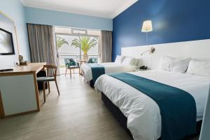 Una habitación de hotel con dos camas y un escritorio. en Saldanha Bay Hotel, en Saldanha