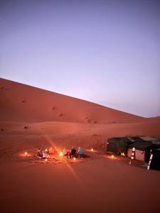 a group of people sitting around a camp in the desert at Gambi Camp in Hassilabied