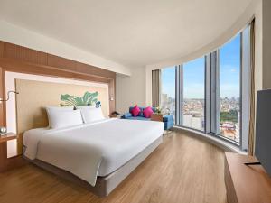 a hotel room with a large bed and large windows at Novotel Saigon Centre in Ho Chi Minh City