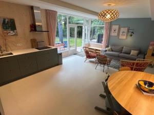 a kitchen and living room with a table and a couch at Fraaie familiebungalow op heerlijk rustige plek in Ouddorp