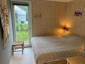a bedroom with a bed and a window and a chair at Fraaie familiebungalow op heerlijk rustige plek in Ouddorp