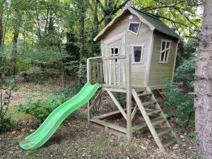 a tree house with a slide in the yard at Fraaie familiebungalow op heerlijk rustige plek in Ouddorp