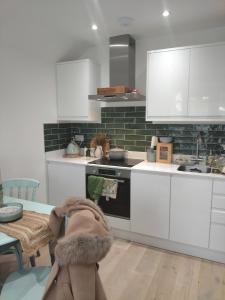 a kitchen with white cabinets and a sink and a table at Beautiful flat in the heart of South London in London +3 photos