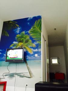 a tv on a wall with a palm tree mural at Apartmani Perić in Bar