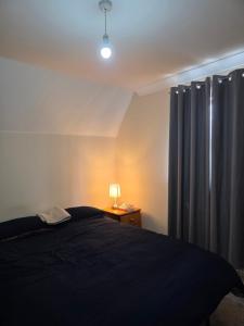 a bedroom with a bed and a lamp and a curtain at Colchester Y5 in Hythe