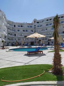 una piscina con sombrilla y una palmera frente a un edificio en Tiba View flat, en Al Adabīyah