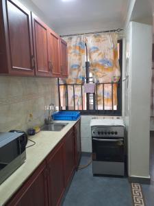 a kitchen with wooden cabinets and a sink and a stove at Ebenezer Apartment, Albert Cook Road in Kampala