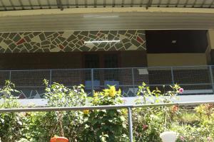 a view of a building with a fence and flowers at Snow drops homestay in Kallar Vattiyar