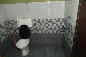 a bathroom with a toilet and a tiled wall at Snow drops homestay in Kallar Vattiyar