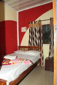a bedroom with a bed with a red wall at Snow drops homestay in Kallar Vattiyar