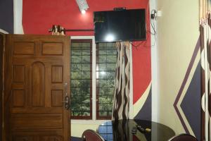 a room with a table and a television on a wall at Snow drops homestay in Kallar Vattiyar