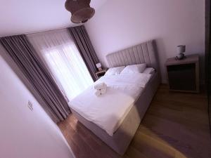 a bedroom with a white bed with a window at Apartments Central Point 11 & Private Garage in Podgorica