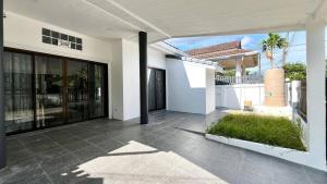 a white house with a patio with a yard at Baiyok Villas near Kathu Waterfall in Ban Huai Luk (1)