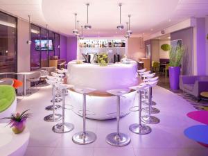 Un restaurante con una gran mesa blanca y taburetes. en ibis Styles Montbéliard, en Montbéliard