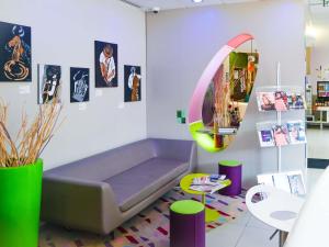Una sala de estar con un sofá y un espejo. en ibis Styles Montbéliard, en Montbéliard
