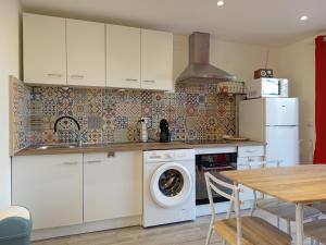 a kitchen with a washing machine and a table at Résidence des 4 saison in Cransac