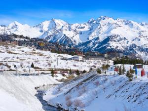 a snowy mountain range with a town and a river at Apartamentos Confort Formigal 3000 in Formigal