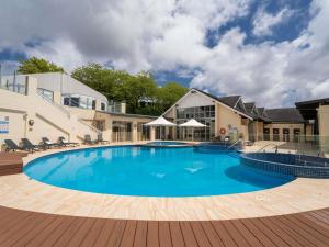 une grande piscine avec des chaises et un bâtiment dans l'établissement Fairmont Resort Blue Mountains MGallery Collection, à Leura