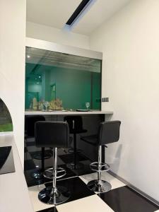 a kitchen with three bar stools and a green wall at Kyiv Kingdom Apartments in Kyiv