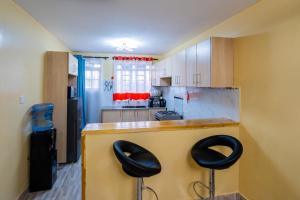 een keuken met twee zwarte krukken aan een aanrecht bij Shwari Home Stays in Kisii