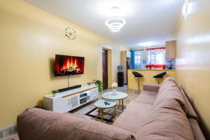 een woonkamer met een bank en een tv bij Shwari Home Stays in Kisii