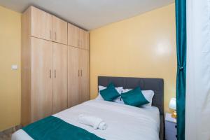 een slaapkamer met een bed met groene en witte kussens bij Shwari Home Stays in Kisii