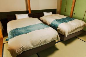 Dos camas una al lado de la otra en una habitación. en 信夫温泉青州, en Fukushima 54 fotos más