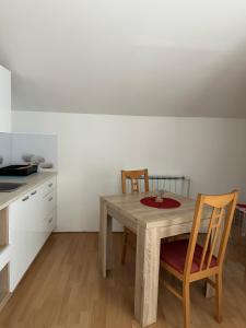 a kitchen with a wooden table and two chairs at Apartments and Wellness Ščavničar in Ljutomer