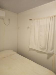 a white bedroom with a bed and a window at Peckes in Balneario Buenos Aires