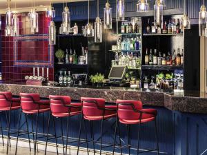 a bar with red bar stools in a room at Mercure Swansea Hotel in Swansea