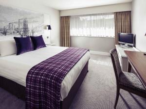 a hotel room with a bed and a desk and a television at Mercure Swansea Hotel in Swansea