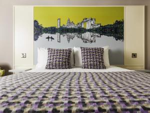 スウォンジーにあるMercure Swansea Hotelの壁に絵が飾られた大きなベッドのある寝室