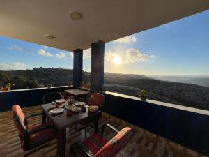 a table and chairs on a balcony with a view at Al-Bustan House& Umm Qais in Um Qeis