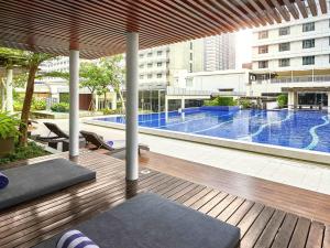 a swimming pool in a building with a wooden deck at Pullman Jakarta Indonesia in Jakarta