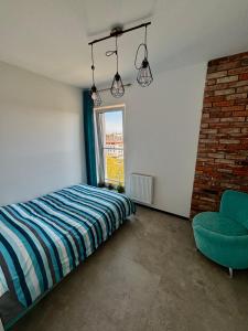 a bedroom with a bed and a chair and a window at Apartament Corner Śrem in Śrem